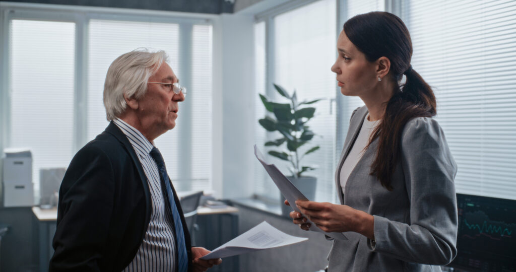 Two financial professionals reviewing documents during a 401(k) compliance review, discussing plan strategy and regulatory requirements in a modern office setting.